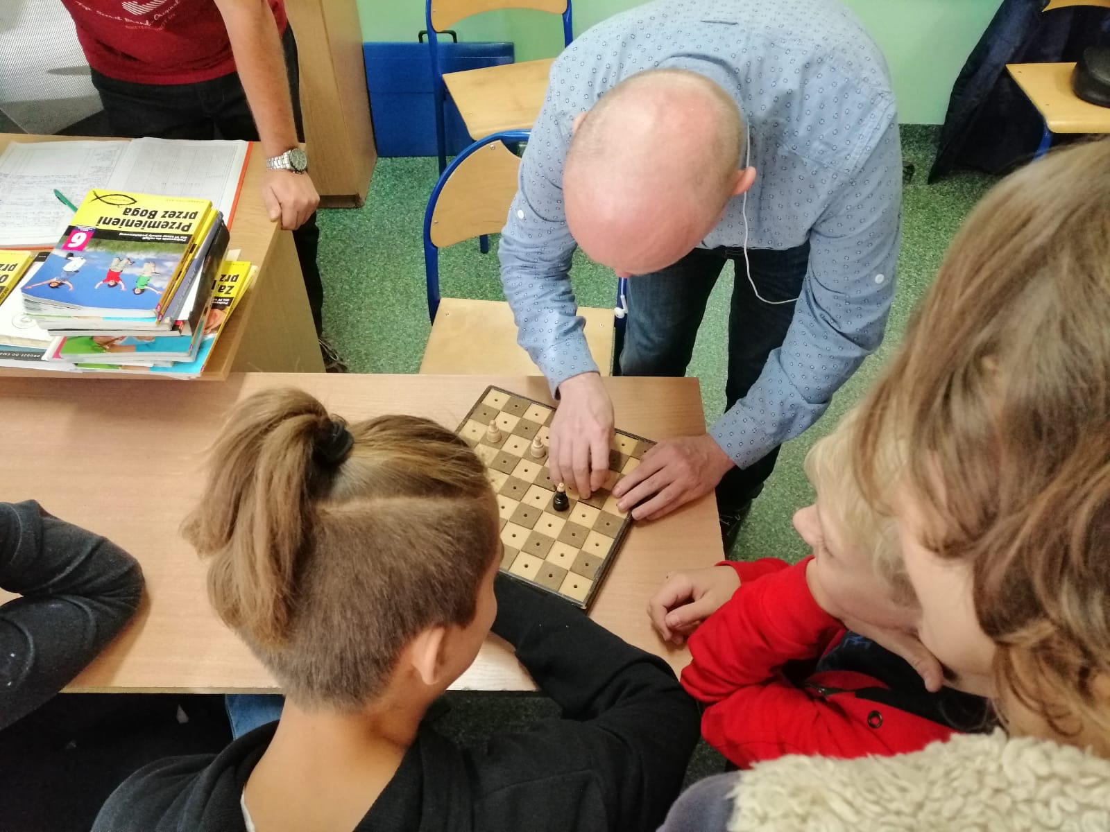 Na zdjęciu Sławek pokazuje uczniom jak grać w szachy dla niewidomych.