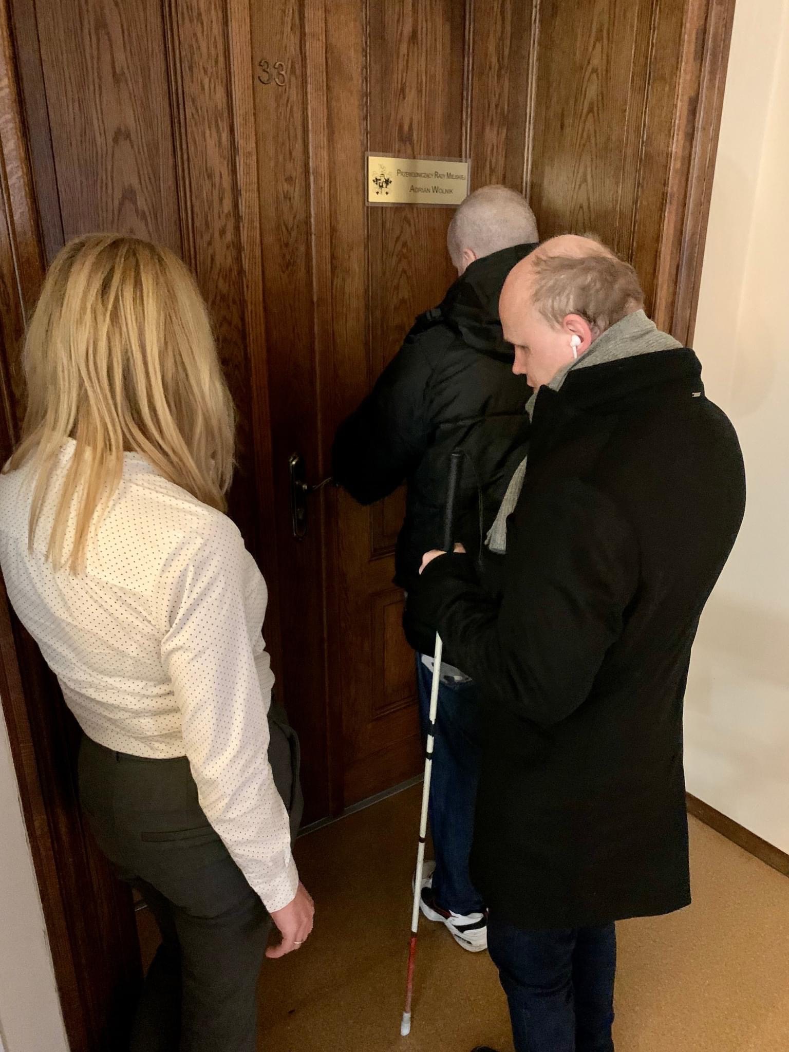 Zdjęcie, Po lewej naczelniczka Wydziału Administracyjnego z Mariuszem Miszudą i Sławomirem Cywką - sprawdzają prawidłowość wykonania tabliczek na drzwiach z pismem Brailla.