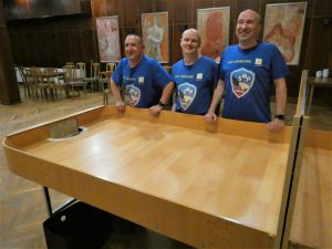 Zdjęcie przedstawia salę konferencyjną w Ośrodków WYDMA PARK w Rowach w której stoi stół do showdowna. Za stołem stoją uśmiechnięci zawodnicy klubu SMP Chorzów, od lewej: Marek, Sławomir, Mariusz.